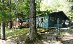Classic knotty pine cottage on scenic all sports Island Lake. This well maintained cottage sets just feet from the sandy beach, overlooking the crystal clear water. Located only 11 miles from downtown Traverse City, yet nestled in the woods with access to