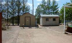 The lot is ready for a mobile home. Utilities are in the alley, 2 work/storage sheds and 1 metal shed. Some of the trees are on a watering system. Several fruit trees and evergreens on the lot. Both front and back decks remain. 2 covered carports,