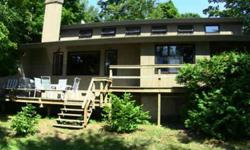 Golden Opportunity to acquire Lake Leelanau lakefront property- under $500k! Unusual contemporary style home perched on sunset-view side of shore line. Huge attached deck, dock, boat hoist, large yard 4 kids, pets & even big kids too. Strong rental