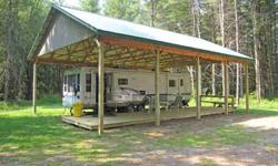 Beautiful wooded lot with clearing. Large travel trailer sheltered under open pole barn connected to an approved septic. Water from a dug well, new wood deck. This is the perfect seasonal camp. Hunt, snowmobile, or build a year round home.Listing
