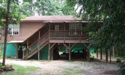 Two bedroom cottage built on tall piers. Has the feel of a mountain retreat. Family room and dining area open to wrap-around deck by sliding doors. The galley kitchen features black appliances, dark counters and open cabinets. The large laundry closet if